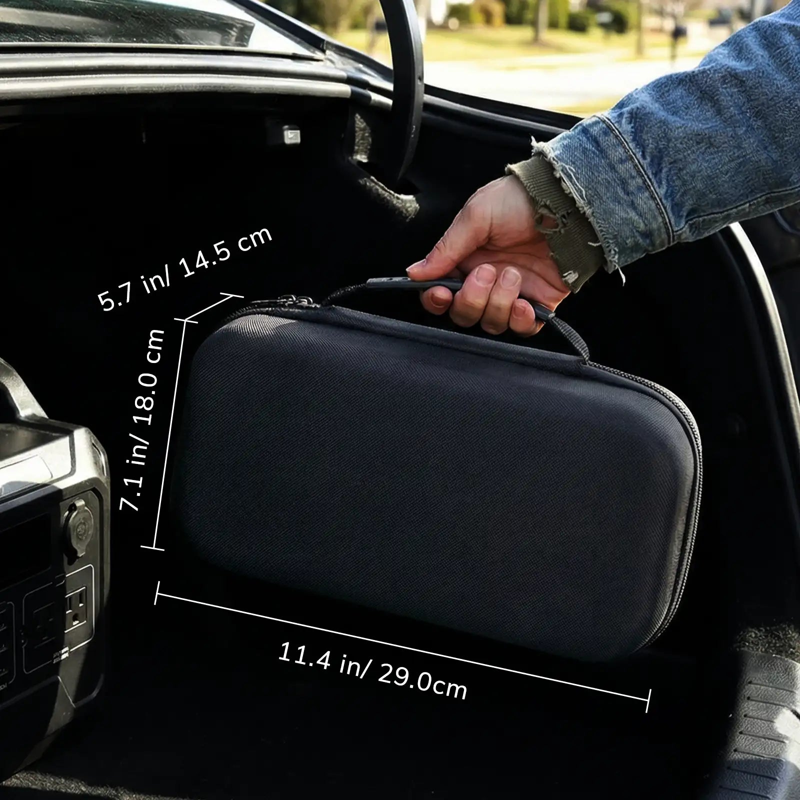 Black carrying case with dimensions being held by a person inside a car.