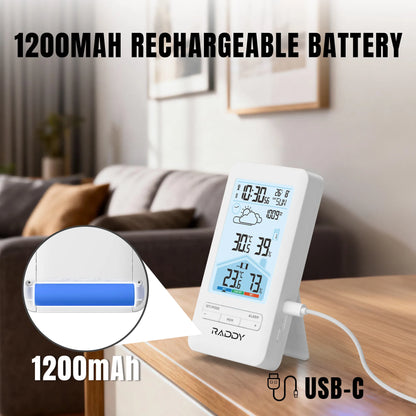 Digital clock with weather display on a table in a living room, featuring a 1200mAh rechargeable battery.